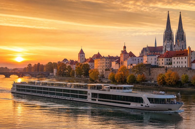 European river cruise vessel on the Danube at sunset beside a medieval town with church spires